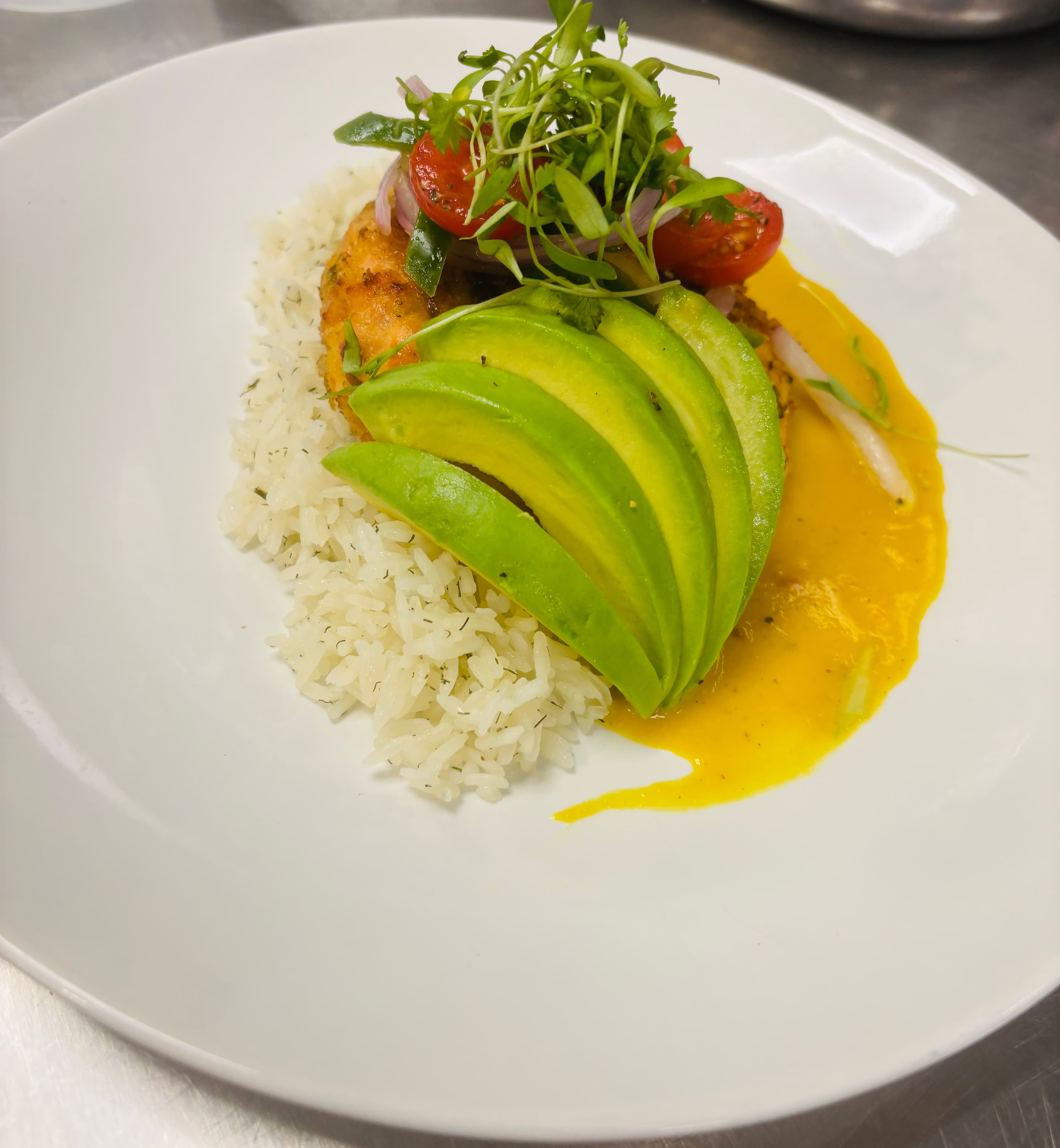 Crab cake with avocado over rice and mango sauce
