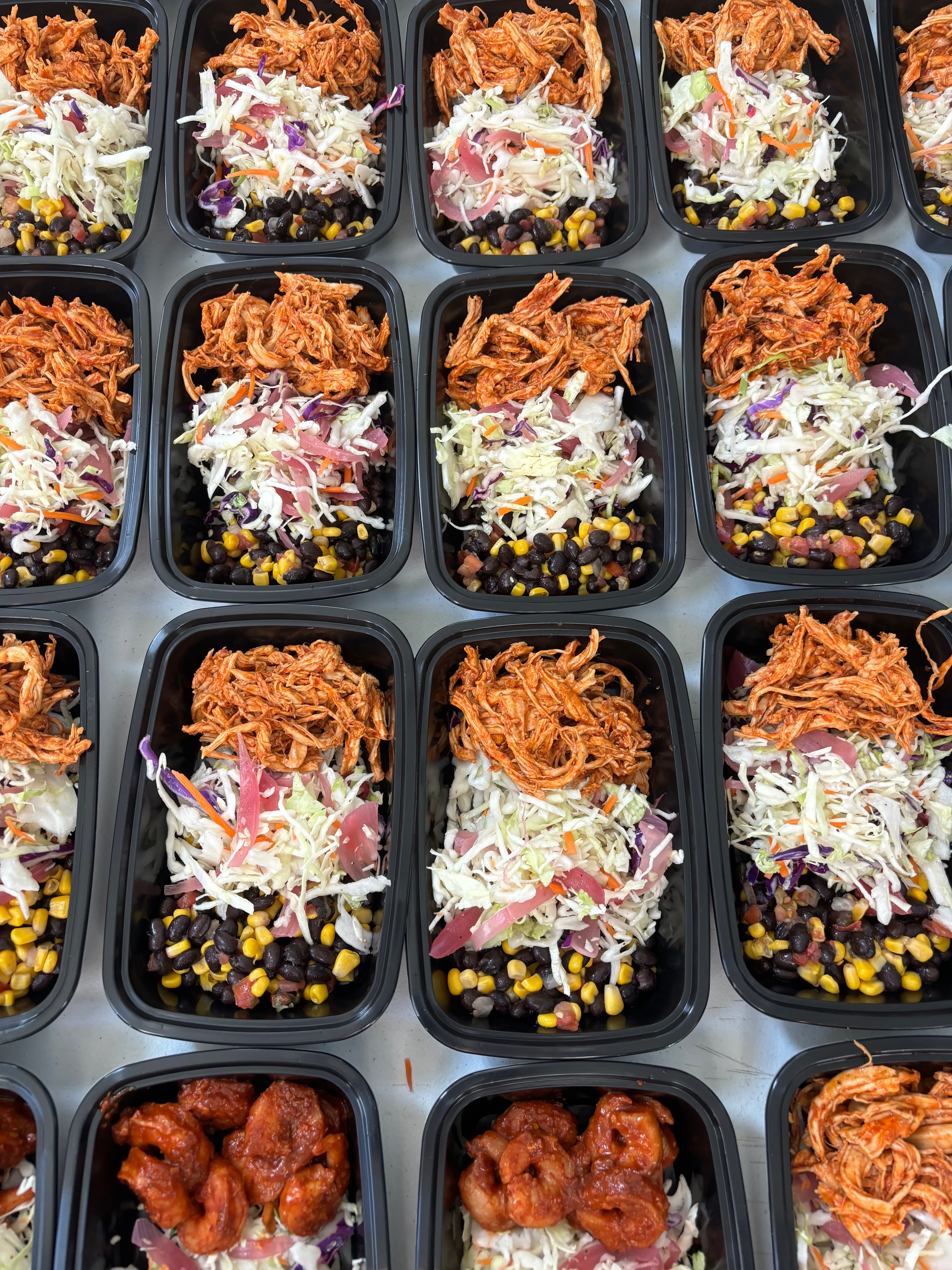 Weekly meal prep containers with jerk-style chicken, slaw, and black bean corn salad