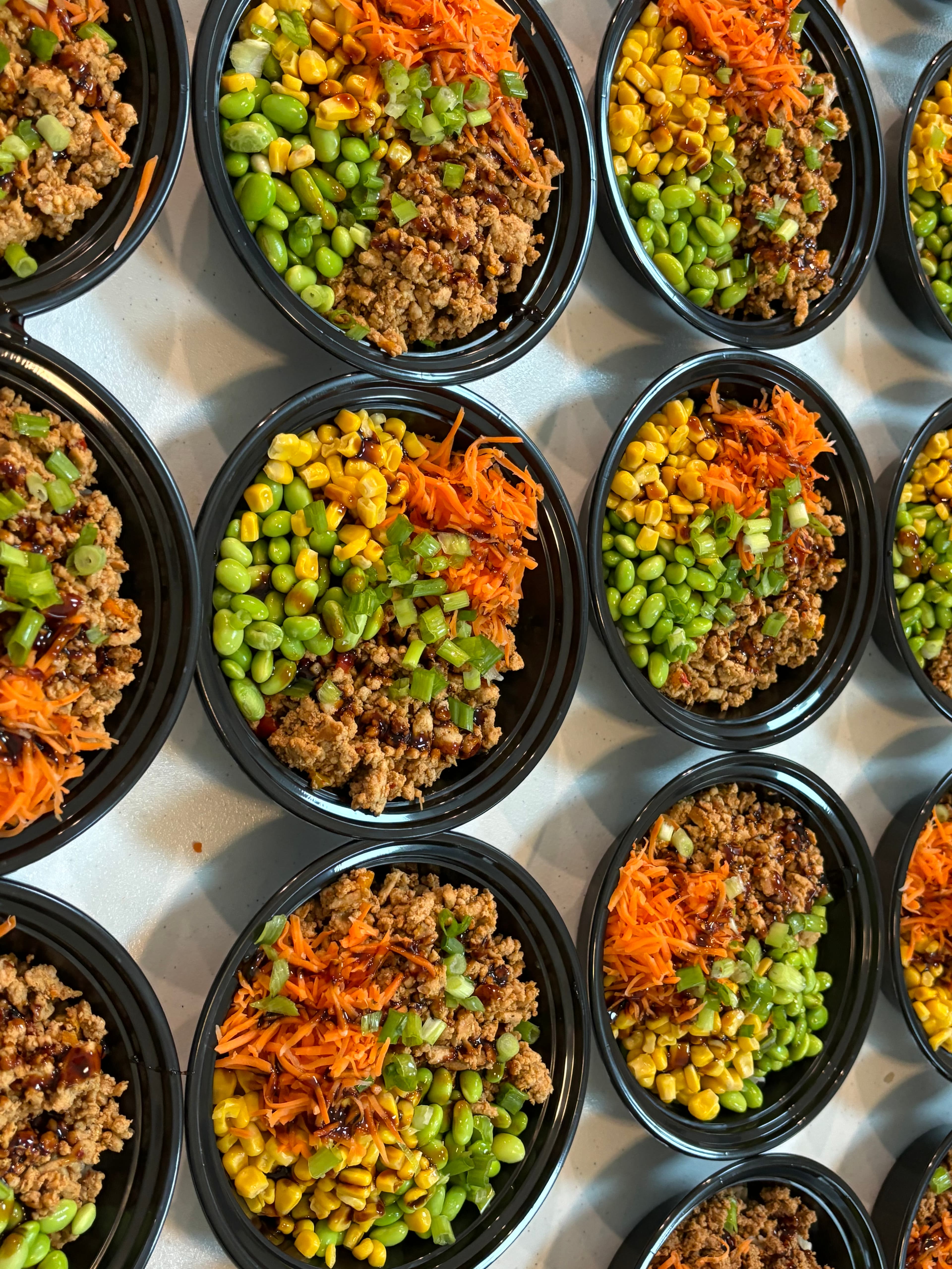 Weekly meal prep bowls with seasoned ground meat, corn, edamame, and carrots